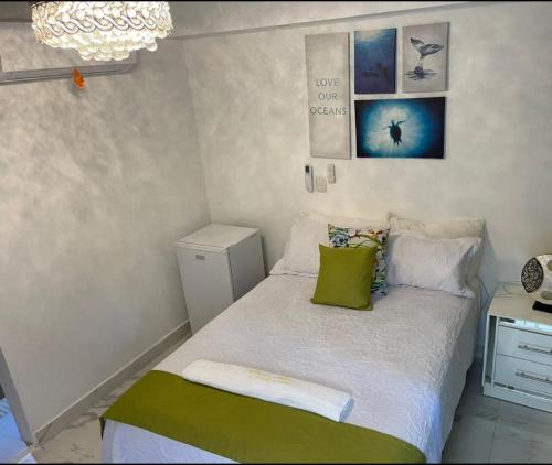 a small bedroom with a bed with green pillows at Room in Guest room - Central Area Bedroom With Common Kitchen, living room in Sosúa