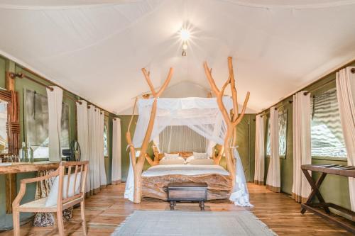 a bedroom with a bed with tree branches on the ceiling at Leopard Safaris Yala in Yala