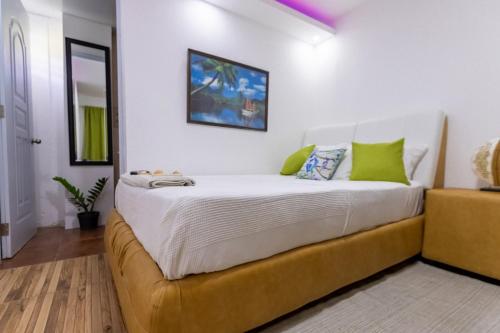 um quarto com uma grande cama branca com almofadas verdes em Room in Guest room - Nice 1br-1bt With Common Picuzzi em Sosúa
