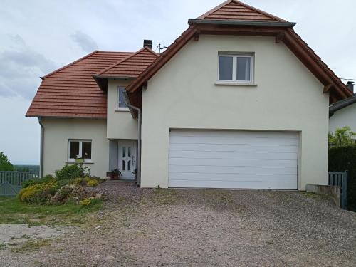 una casa blanca con una puerta de garaje blanca en Au fil du Bonheur studio, en Surbourg