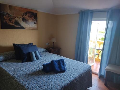 a bedroom with a bed with blue pillows and a window at Casa Villa El Olivar in Huelva