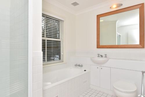 a white bathroom with a tub and a sink and a toilet at Villa 2br Grange Villa located within Cypress Lakes Resort in Pokolbin