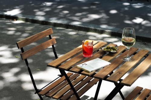 a wooden table with a glass of wine and a book at Hôtel Léopold - Orso Hotels in Paris
