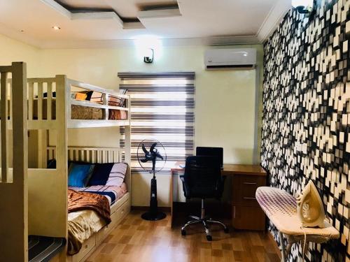 a bedroom with a bunk bed and a desk and a chair at Harmony Homes Ibadan: Modern 3BR Duplex in Oluyole in Ibadan