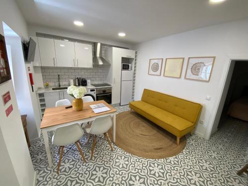 a living room with a yellow couch and a table at Estudio da Moeda in Évora