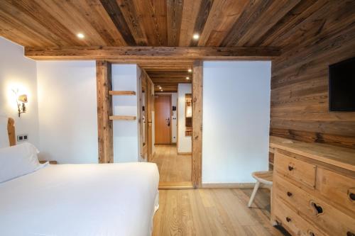 a bedroom with a white bed and wooden walls at Chalet-Hôtel Hermitage in Chamonix-Mont-Blanc