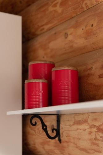 three red cups are sitting on a shelf at Piešupīte in Staburags