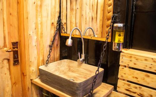 a wooden bathroom with a wooden sink chained to a wall at Redhill Container House & Private Spa in Nairobi