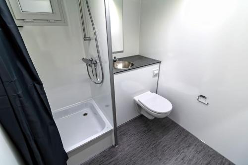 a white bathroom with a shower and a toilet at Under Canvas Bornholm in Østermarie