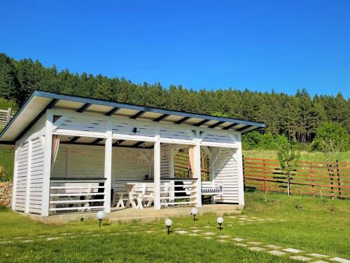 a small white shed with two benches in a field at NOIA Caban in Piatra Neamţ