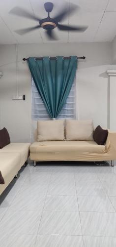 Raudah Homestay Kuala Nerang في Kuala Nerang: أريكة في غرفة مع مروحة سقف