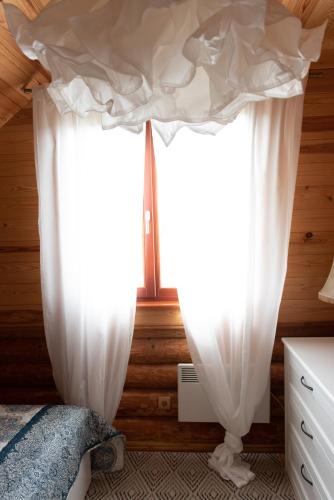 a pair of white curtains in a bedroom at Piešupīte in Staburags