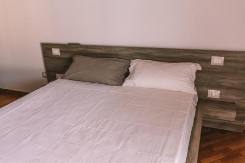 a bed with a wooden headboard and two pillows at Mela e Pera in Treviglio