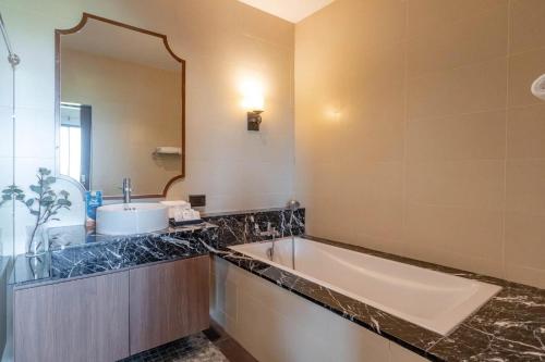a bathroom with a tub and a sink and a mirror at The Cavalli Casa Resort in Phra Nakhon Si Ayutthaya