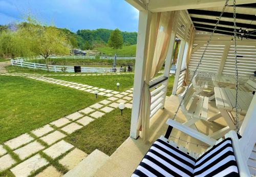 a porch with a swing and a field of grass at NOIA Caban in Piatra Neamţ