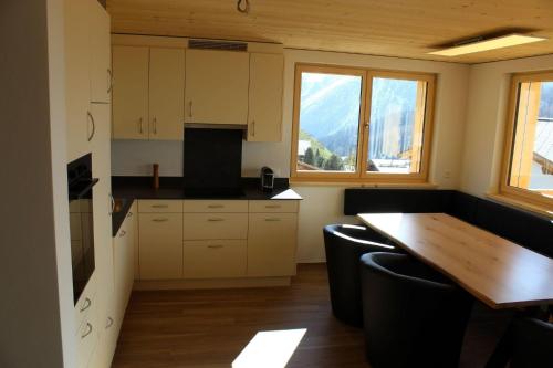 a kitchen with a wooden table and some windows at Chalet Sternenhimmel in Arosa