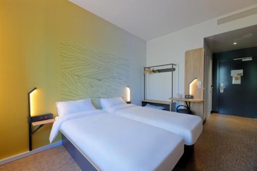 a bedroom with a large white bed with a green wall at B&B HOTEL Le Touquet in Cucq