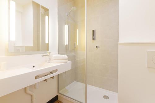 uma casa de banho branca com um lavatório e um chuveiro em B&B HOTEL Le Touquet em Cucq