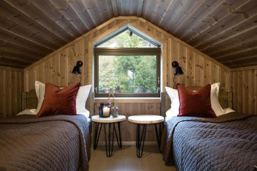 zwei Betten in einem kleinen Zimmer mit Fenster in der Unterkunft Cozy modern holiday villa with electric car charging, sauna and fireplace in Øyer