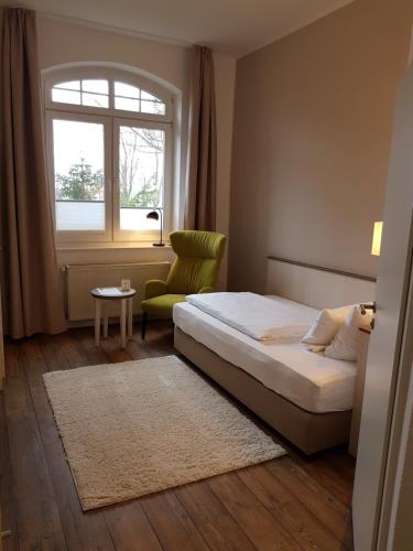 a bedroom with a bed and a chair and a window at Ringhotel Villa Margarete in Waren
