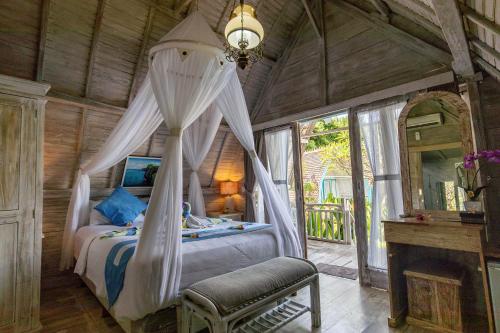 - une chambre avec un lit à baldaquin et une cheminée dans l'établissement Bakung Cozy Cottage, à Nusa Penida
