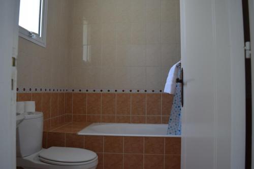 a bathroom with a toilet and a bath tub at Eden Heights Sea View Apartment 203 - By IMH Travel & Tours in Paphos City