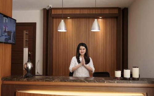 a woman standing in front of a mirror praying at SENAYAN SUITES in Jakarta