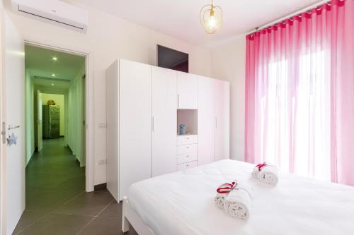 a bedroom with a white bed and pink curtains at GuestHost - Salento Sole e Mare Luxury with Pool in Lendinuso