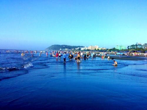 un grupo de personas de pie en el agua en la playa en Tuấn Đạt Luxury FLC Sầm Sơn en Sầm Sơn