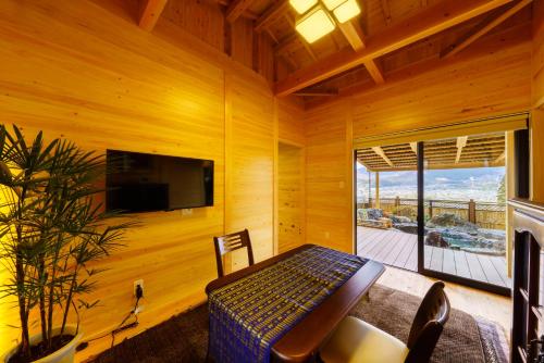 a wooden room with a bed and a tv and a balcony at Yufuin-Sanso Waremokou in Yufuin