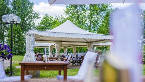 a white tent with tables and chairs in a park at Seepark Hotel am Wandlitzsee in Wandlitz