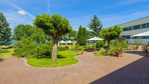 a courtyard with tables and trees and a building at Seepark Hotel am Wandlitzsee in Wandlitz