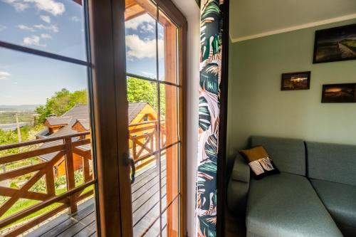 a living room with a couch and a sliding glass door at Centrum Spokoju - Domki w Karkonoszach in Podgórzyn