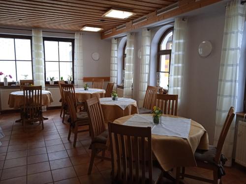 a dining room with tables and chairs and windows at Pension Drei Elstern in Schierke