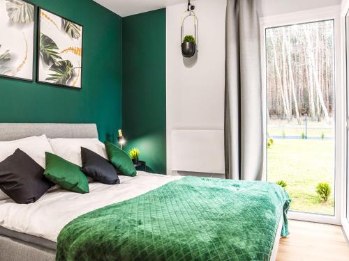 a bedroom with a bed with green walls and a window at Osada Blisko Natury in Gniezno