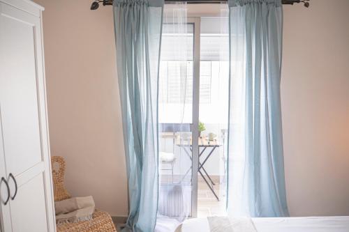 a bedroom with a bed and a window with blue curtains at Apartamento AGUADULCE in Sanlúcar de Barrameda