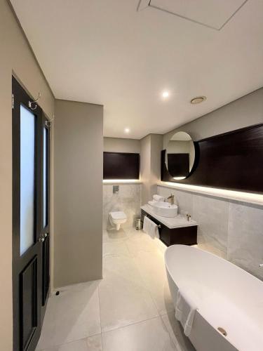 a bathroom with a tub and a toilet and a sink at Premier Hotel Cape Town in Cape Town