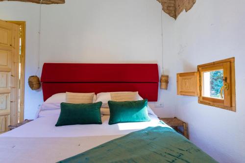 a bed with a red headboard and two green pillows at Hotel Torre Barcelona in Sant Cugat del Vallès