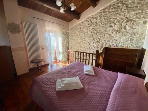 a bedroom with a purple bed and a stone wall at Pacentro Dimora del Castello in Pacentro