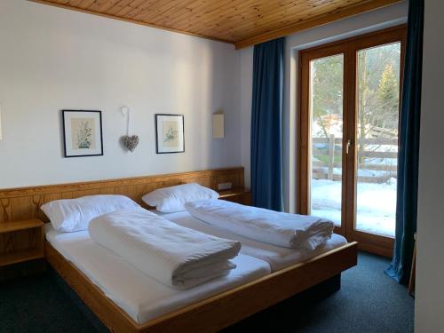 a bedroom with a bed with white sheets and a window at Panoramaalm - Ski in - Ski out in Bad Kleinkirchheim