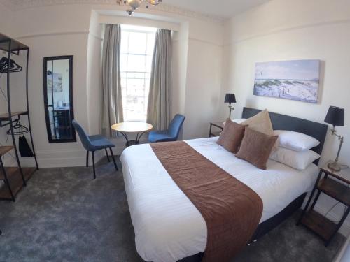 ein Hotelzimmer mit einem Bett, einem Tisch und Stühlen in der Unterkunft The Grove Falmouth in Falmouth
