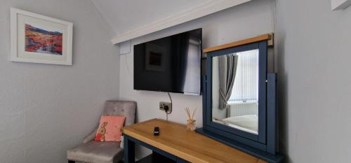 a mirror on a wall with a chair and a desk at Bonny Brae House by Woodland Park in Windermere