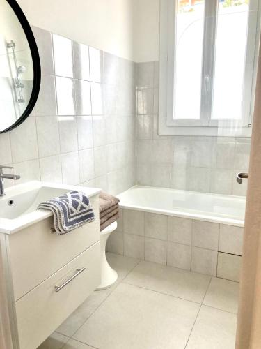 une salle de bain blanche avec une baignoire et un lavabo dans l'établissement Edouard VII, à Menton