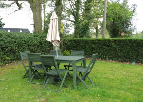una mesa y sillas con una sombrilla en la hierba en The Middlewood - Luxury self contained retreat, en Adlington