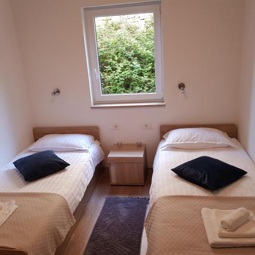 two beds in a room with a window at Apartment Katerina in Supetar