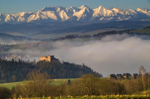 a foggy valley with a castle and mountains in the background at Pokoje Gościnne Barka - 300m do RESTAURACJI - 900m do JEZIORA i VELO CZORSZTYN in Kluszkowce
