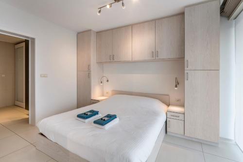 um quarto com uma cama branca e armários em Gelijkvloers zeedijk appartement - lichtrijk en modern em Blankenberge