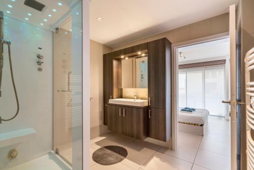 2 vistas para uma casa de banho com um lavatório e um chuveiro em Gelijkvloers zeedijk appartement - lichtrijk en modern em Blankenberge