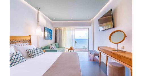 a bedroom with a bed and a desk and a mirror at Petra Mare in Ierápetra