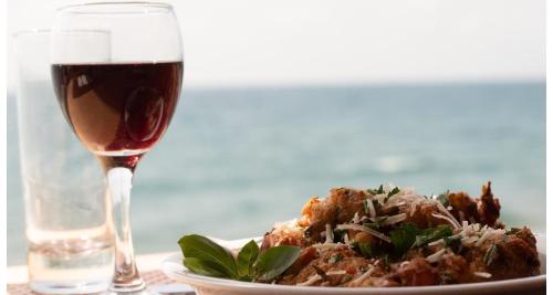 a glass of wine next to a plate of food at Petra Mare in Ierápetra
